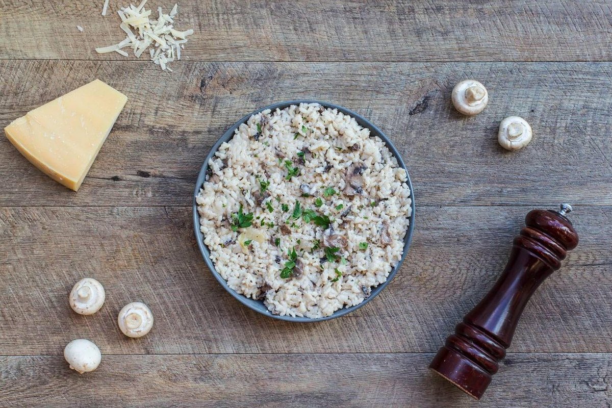 Risotto aux champignons dans un bol avec parmesan et moulin à poivre