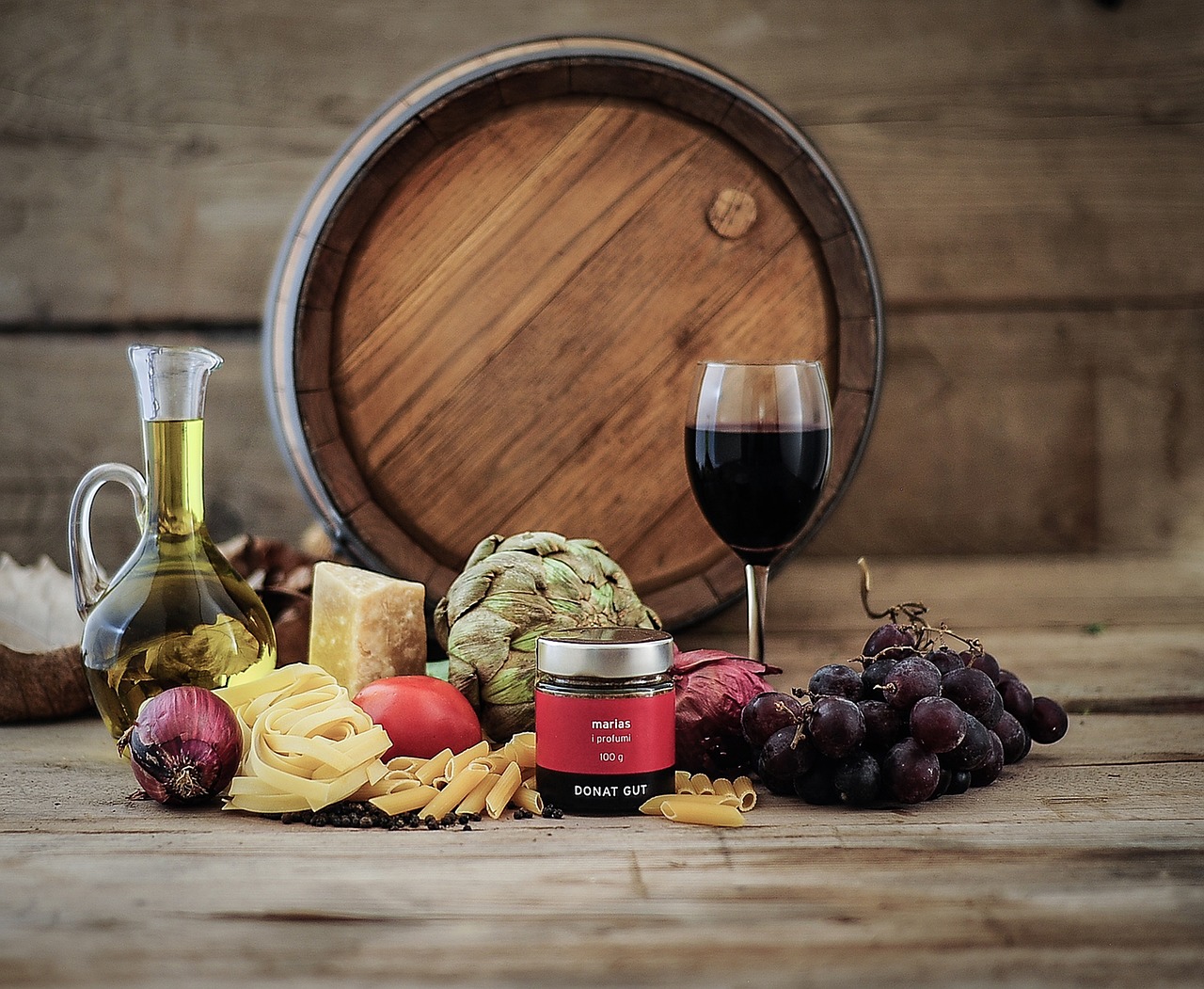 Deux verres de vin, un rouge et un blanc, posés près d'une assiette de pâtes italiennes.