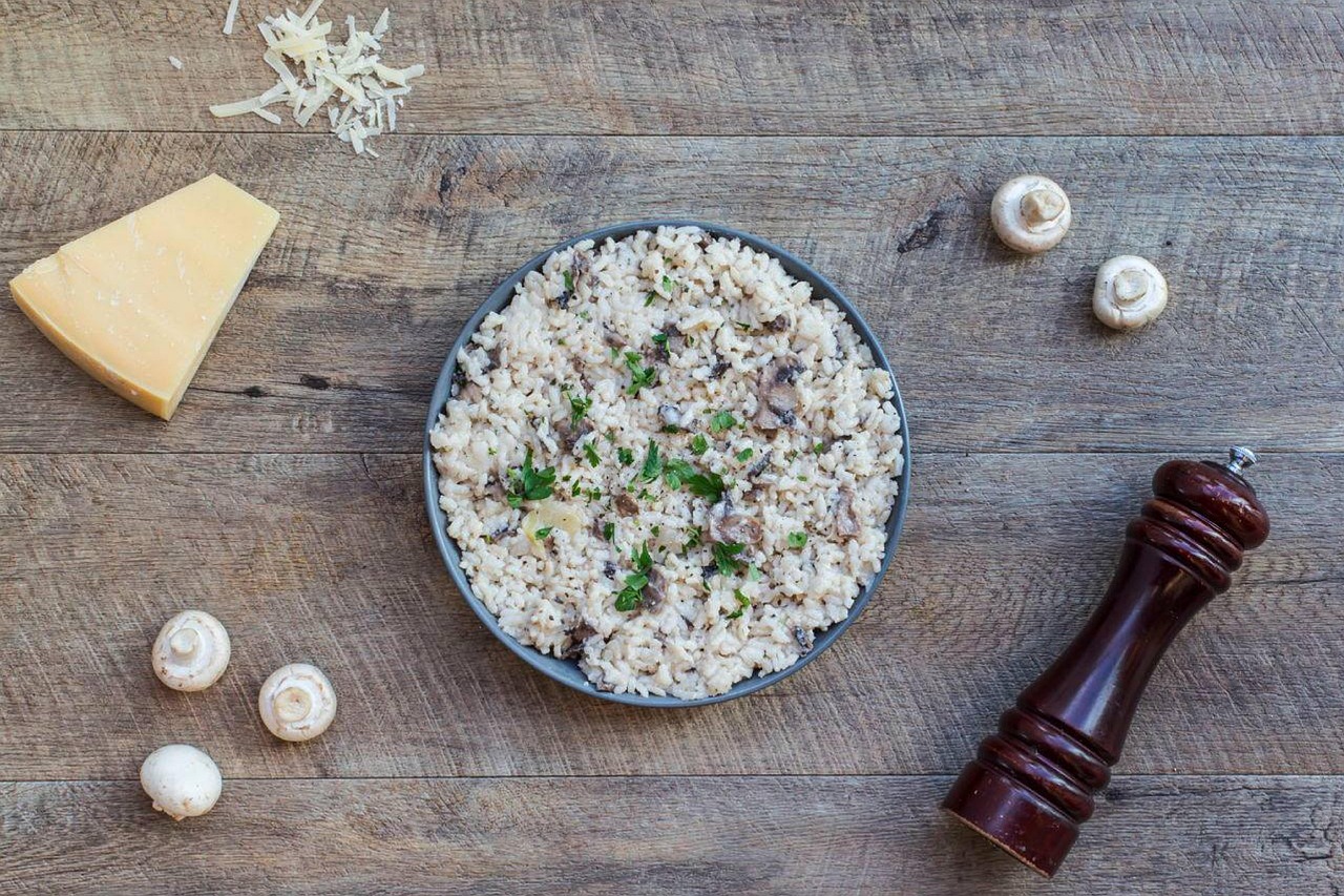 Risotto crémeux au parmesan dans une assiette avec un morceau de parmesan, cuisine italienne maison